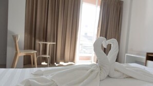 Quarto de hotel com cama, uma cadeira e cortinas.