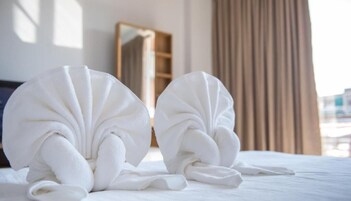 Dos toallas dobladas cuidadosamente sobre una cama con cabecera de madera y un espejo al fondo.