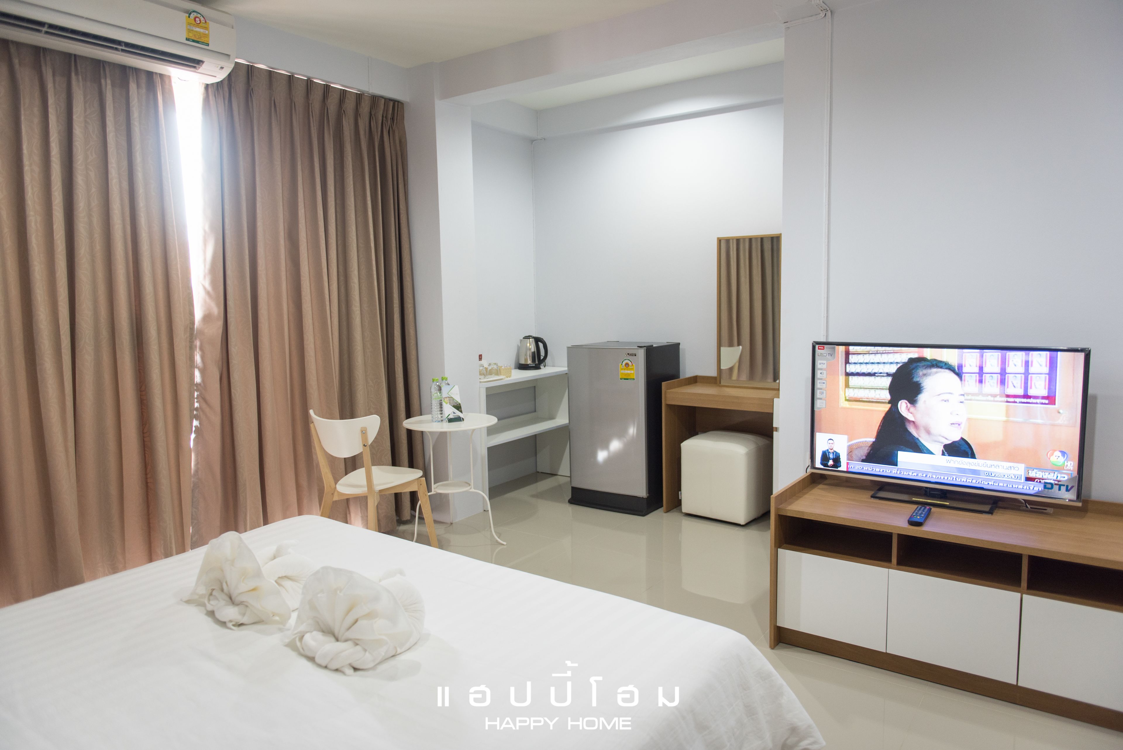 Habitación de hotel con cama, escritorio, televisor y refrigerador.
