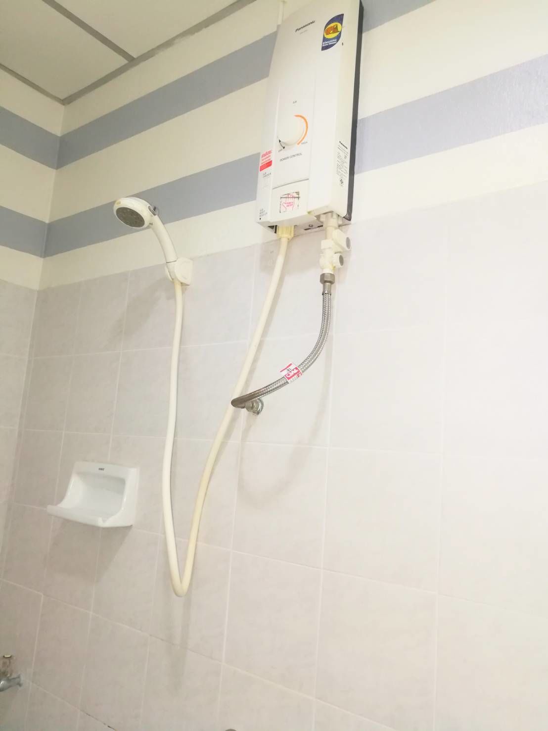 Um chuveiro com um chuveiro manual e painel de controle fixado na parede.