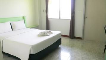 Een hotelkamer met een bed, een raam met gordijnen en een deur.