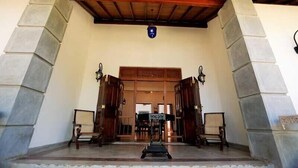 A grand entrance with a wooden ceiling and stone pillars, leading to a traditional interior. - Arunalu Lake Front (Koggala)
