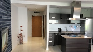 A modern kitchen with a central island, stainless steel appliances, and a wooden door in the background. - JAB Apartments Panoramika i Bandurskiego (Szczecin)