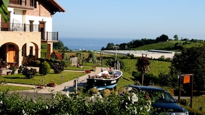 Un edificio de dos plantas con un balcón, un barco lleno de flores en la entrada y vistas al mar.