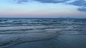 Nær stranden, hvit sand, solsenger og parasoller