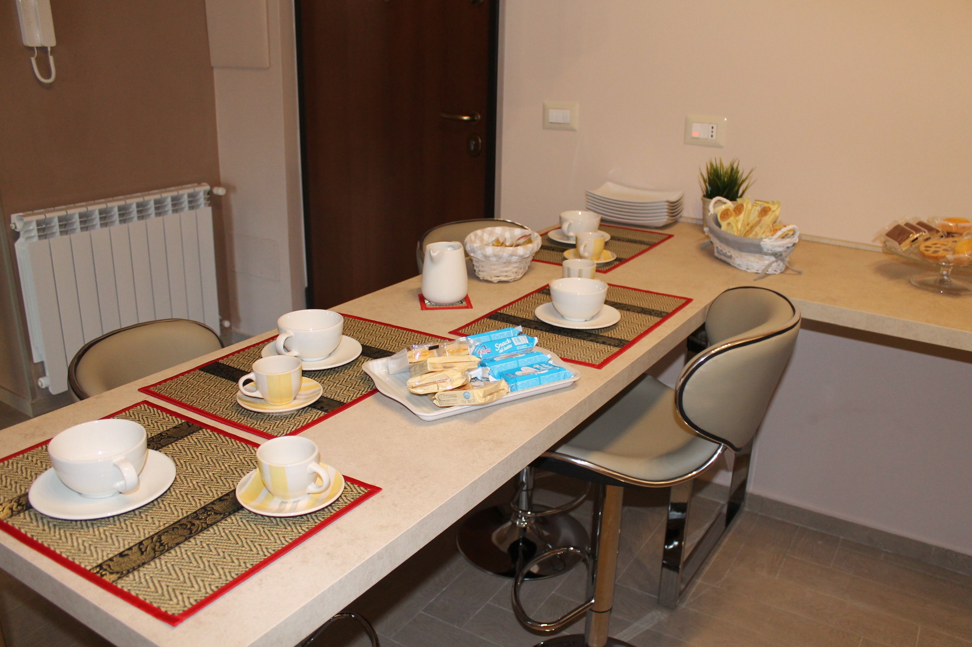 Une table de petit-déjeuner dressée avec des tasses, des bols et des viennoiseries.