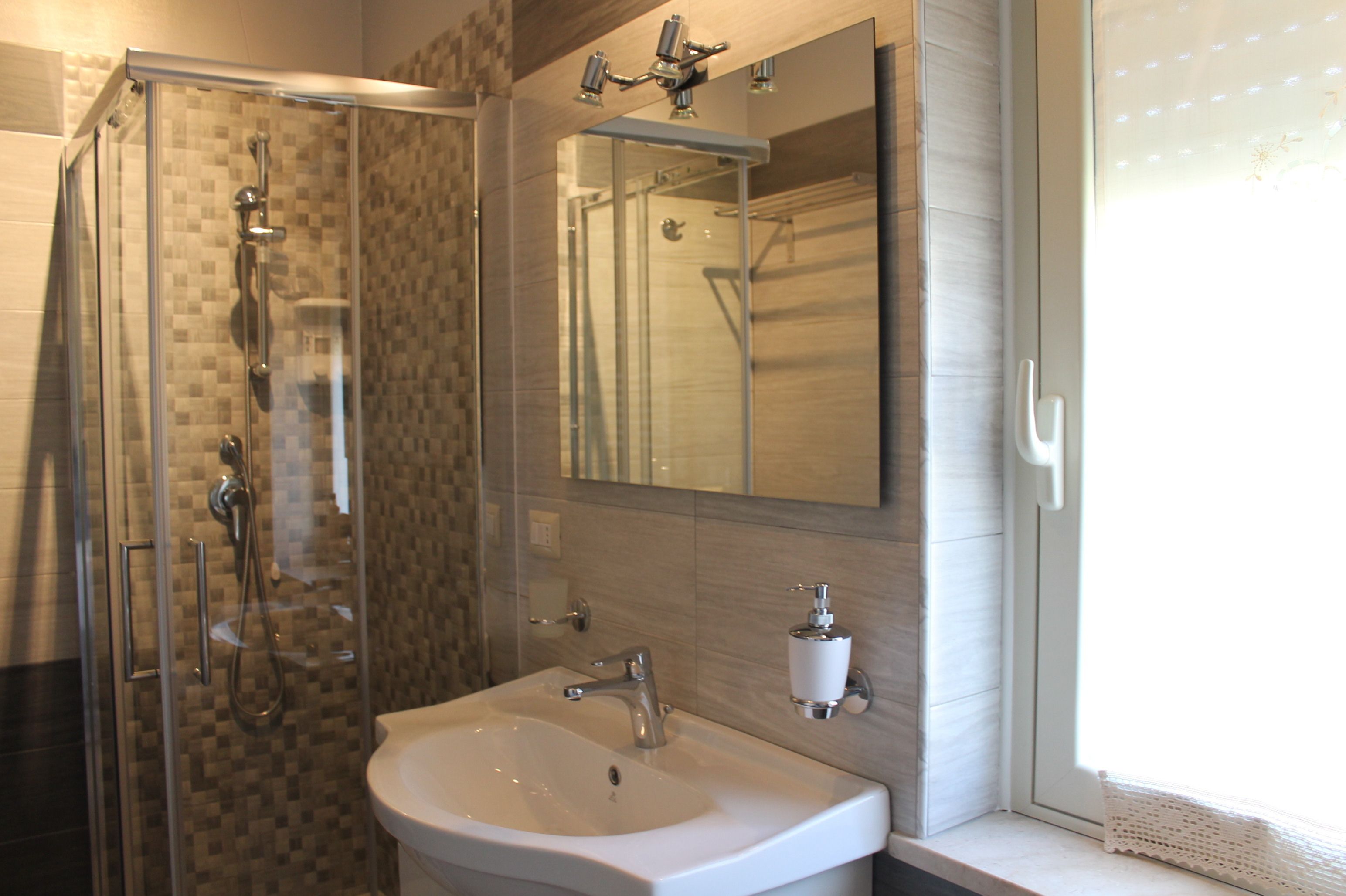 A modern bathroom with a glass shower enclosure, a sink, and a mirror.