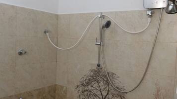 Un baño con ducha, secador de pelo y barra para toallas.