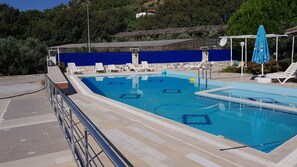 Una piscina al aire libre de temporada, sombrillas
