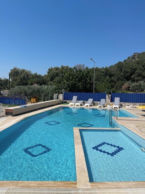 Una piscina al aire libre de temporada, sombrillas