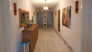 Un pasillo con un armario de madera, un cesto de basura, un espejo y un cuadro en la pared.