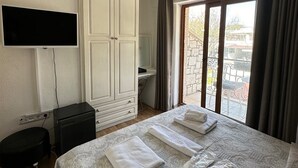 Habitación de hotel con cama, televisor, armario, escritorio y vistas al exterior.