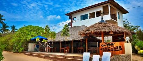 Un restaurante frente al mar con techo de paja y un letrero que dice "ZIZAB".