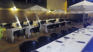 Un espace de restauration en plein air avec des tables dressées pour les clients, protégé par des parasols blancs et entouré de chaises.