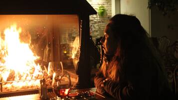 A person sitting at a table with a fire visible through a glass partition, a salt shaker, and a glass on the table.
