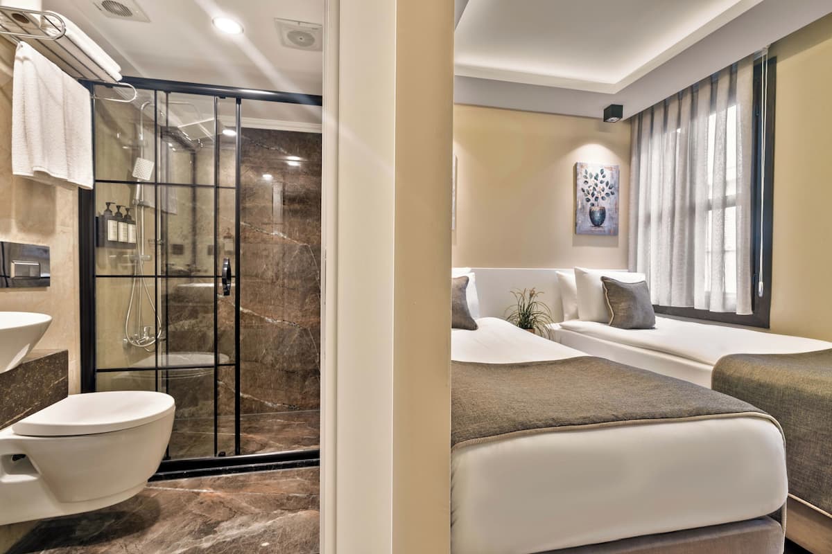 A modern bathroom with a glass shower enclosure, a white toilet, and a marble floor.