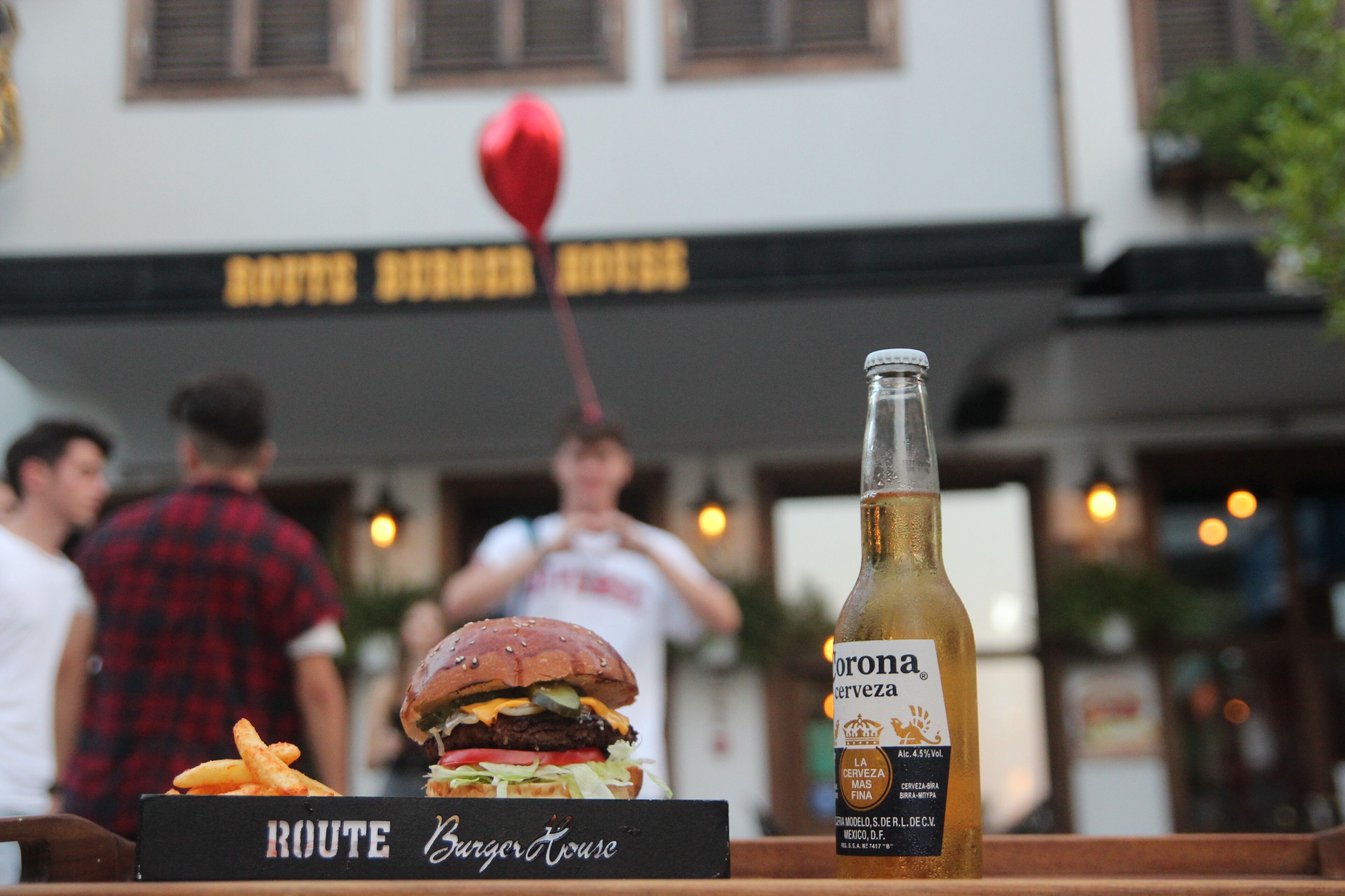 Ein Burger und eine Flasche Corona Bier auf einem Tisch, mit einem Schild, auf dem 'ROUTE Burger House' steht.