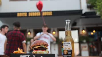 Ein Burger und eine Flasche Corona Bier auf einem Tisch, mit einem Schild, auf dem 'ROUTE Burger House' steht.