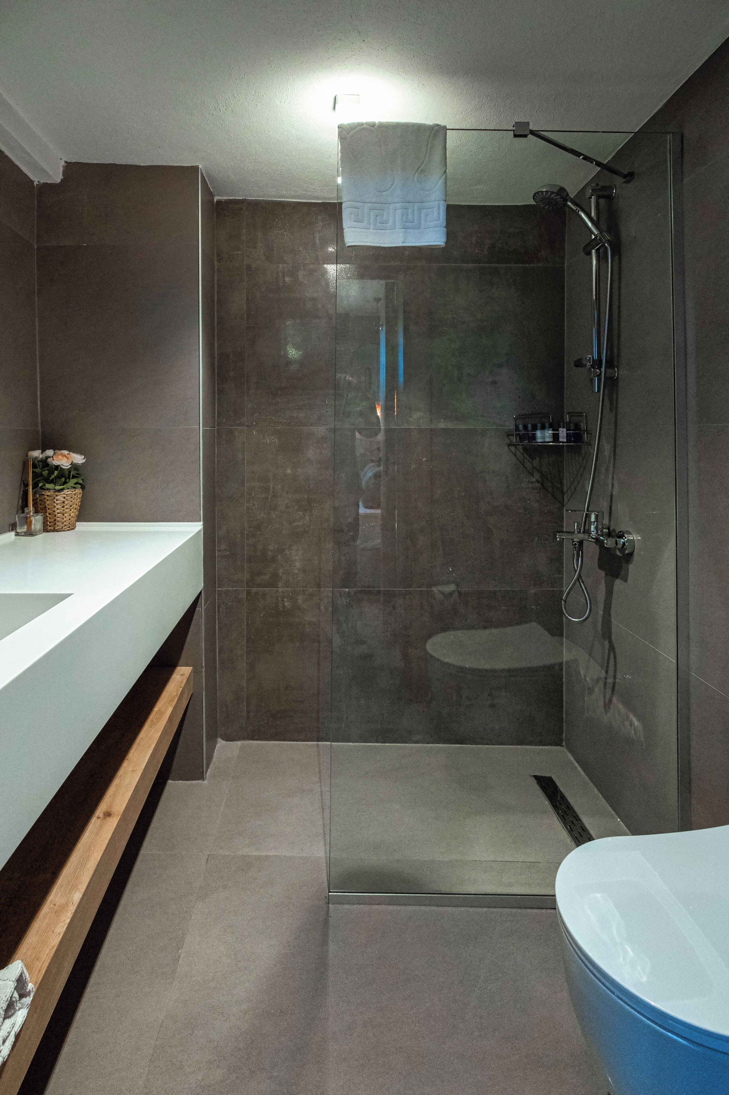 A modern bathroom with a glass-enclosed shower, a white sink, and a blue bathtub.