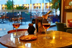A table with two glasses of wine, a bottle of champagne, and a plate of sliced fruit.