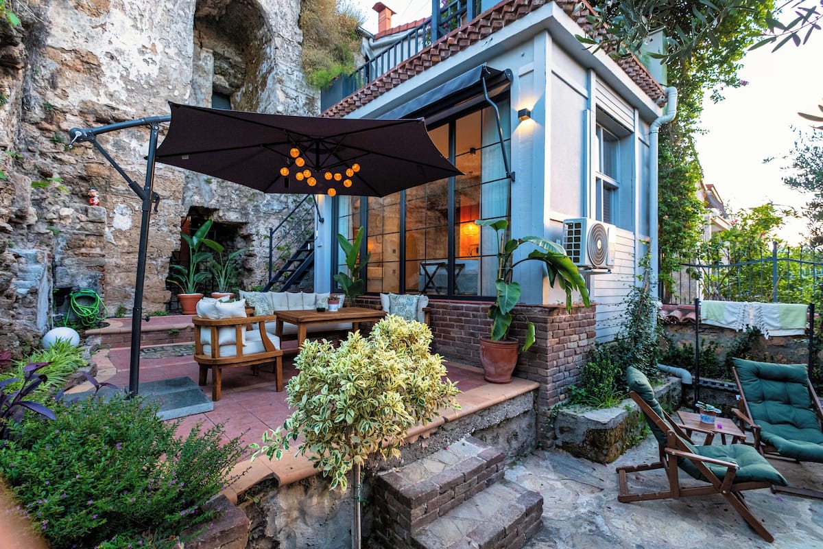 A patio with outdoor furniture, a large umbrella, and potted plants.