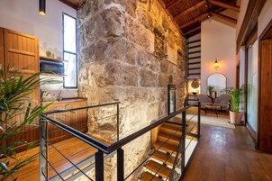 A rustic interior with a stone wall, wooden staircase, and a kitchen area with wooden cabinets and a sink.