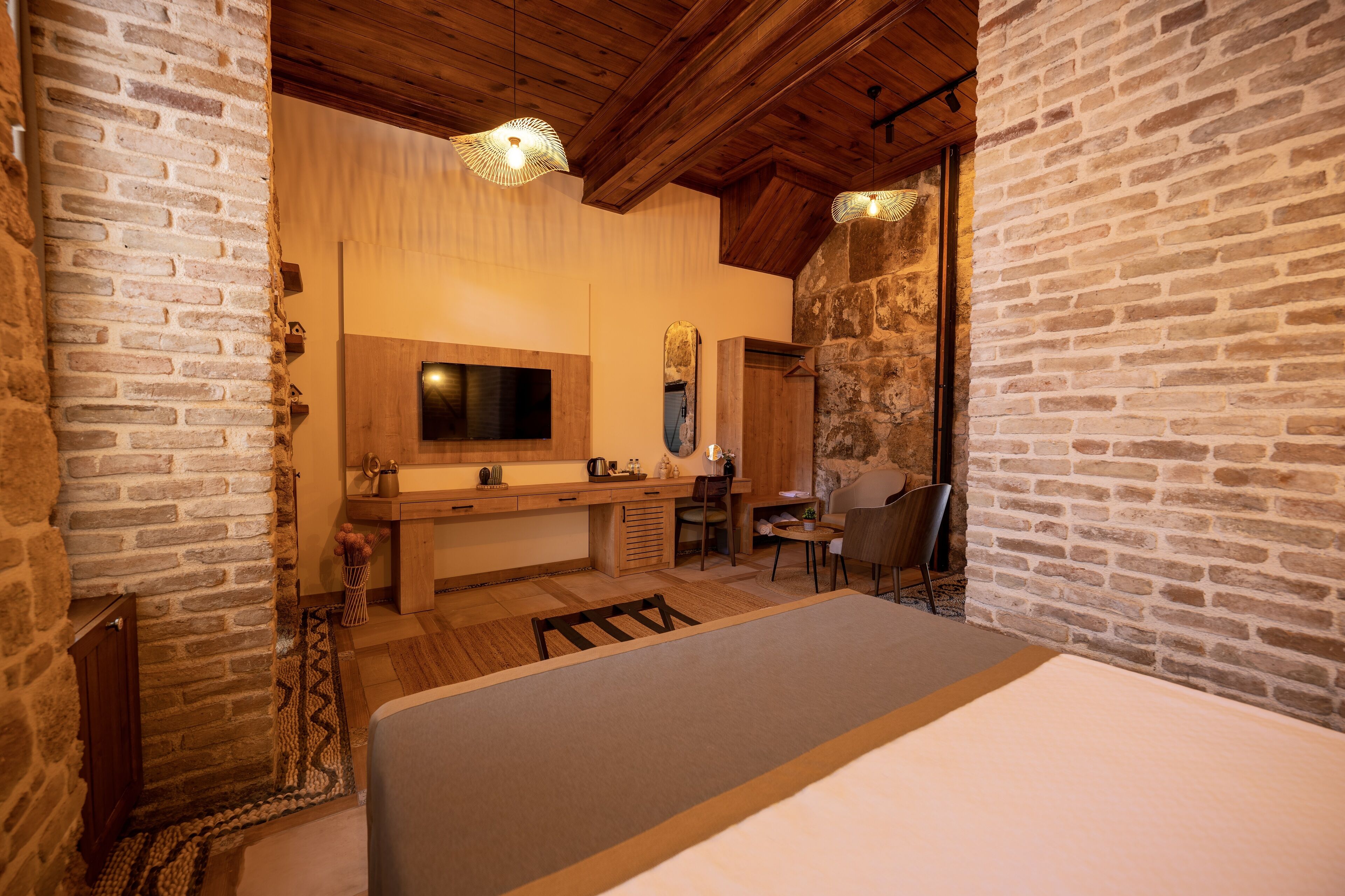 A cozy room with a bed, a wooden desk, a chair, and a television.