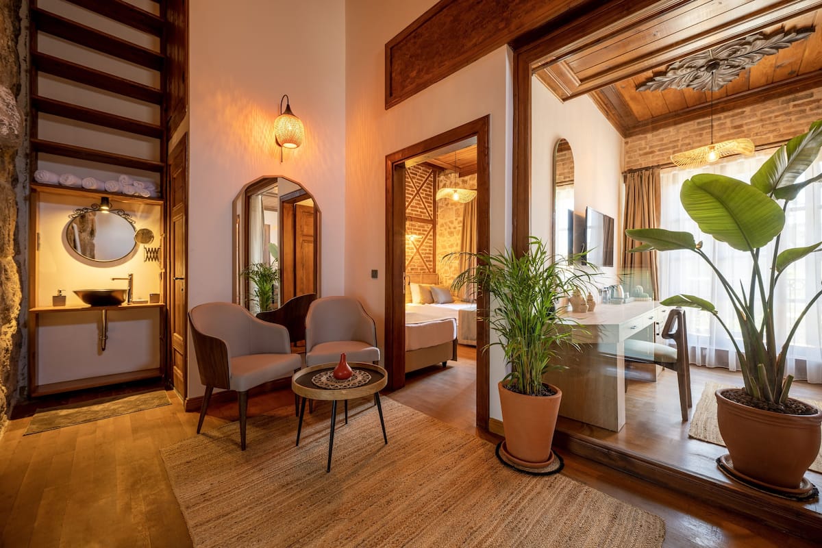 A cozy living room with a fireplace, comfortable seating, and a large mirror reflecting the room.