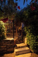 A stone staircase leading to a wooden deck surrounded by lush greenery and flowering plants.