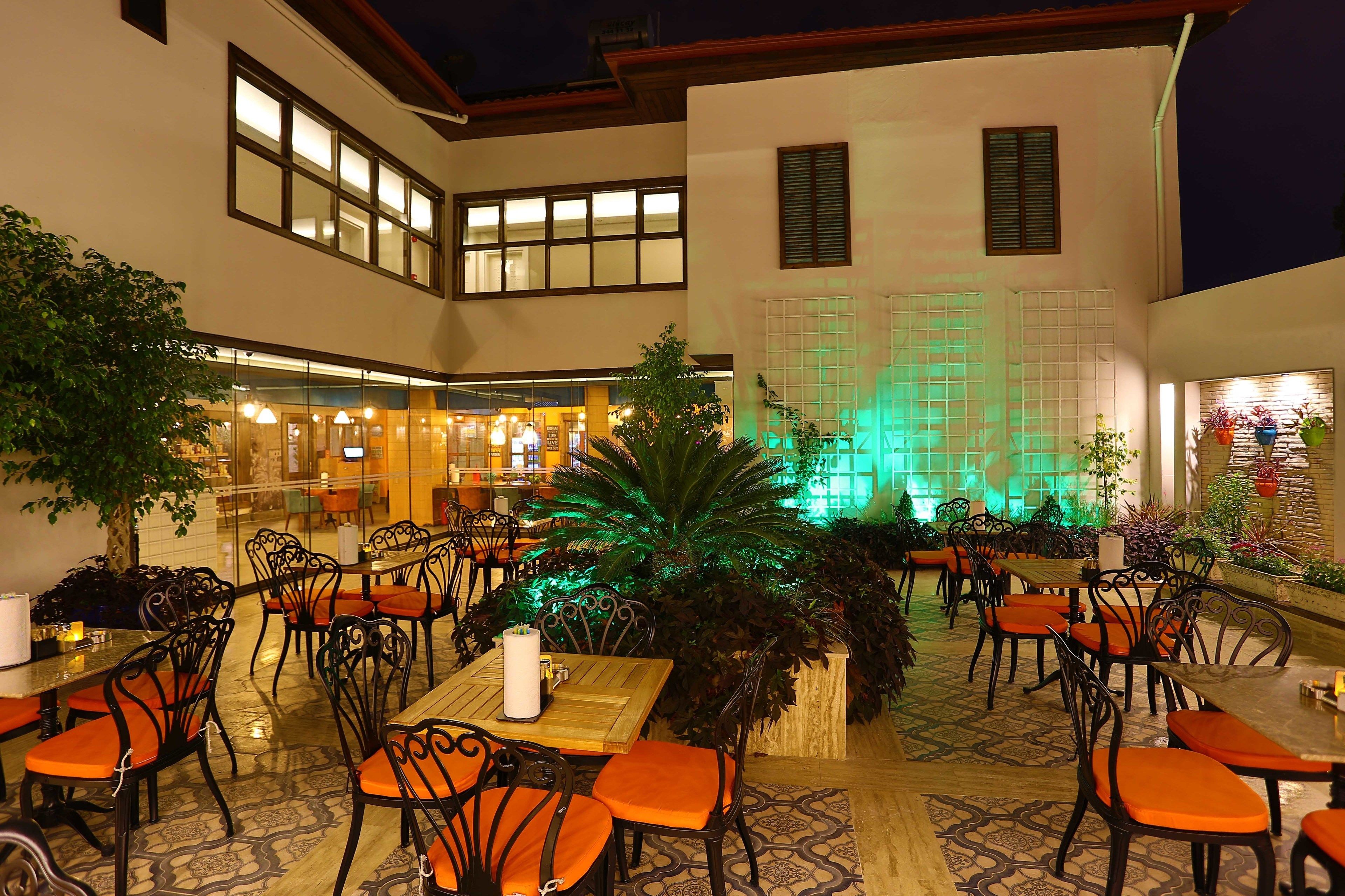 An indoor dining area with tables and chairs, a fountain, and potted plants.