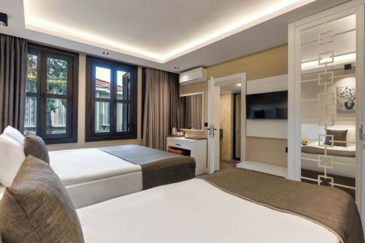 Een hotelkamer met twee bedden, een bureau, een televisie en een badkamers deur.