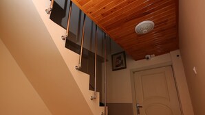A wooden staircase with metal railings, a white door, and a small storage box on the floor. - Emiroglu Konak (Safranbolu)