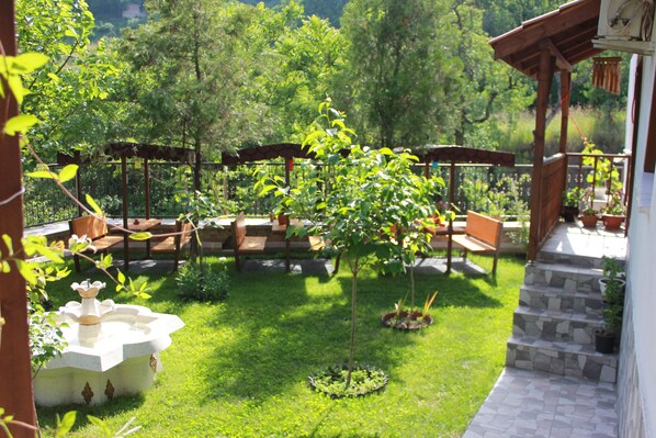 Un patio con muebles de exterior, un pequeño árbol y una escalera de piedra que lleva a un área cubierta.