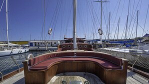 A wooden deck with a curved bench and a central mast. - Tersane IV (Palermo)