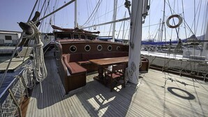 A wooden deck with a bench and table, ropes, and a lifebuoy. - Tersane IV (Palermo)
