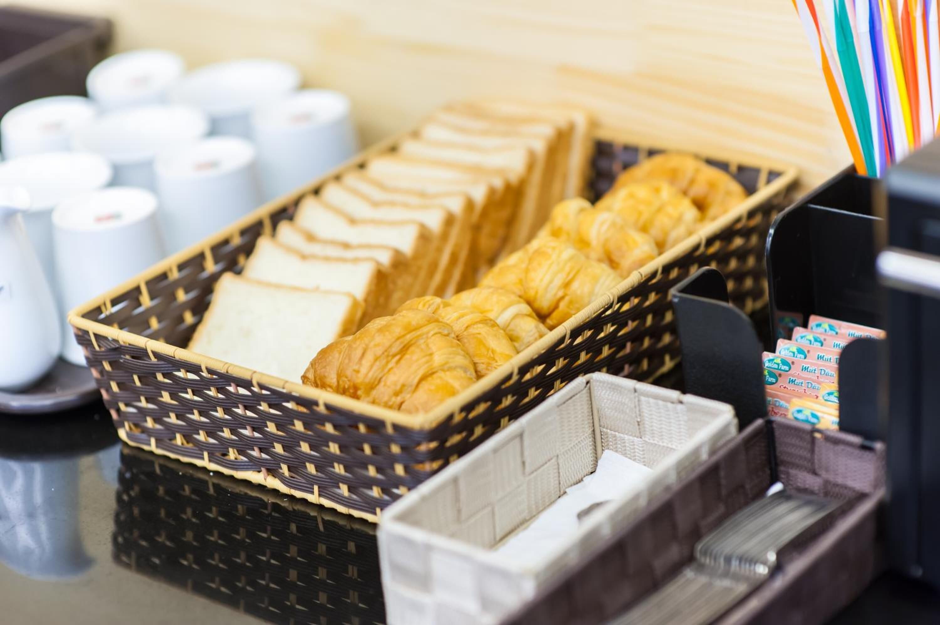 A breakfast buffet with croissants, muffins, and hot drinks.