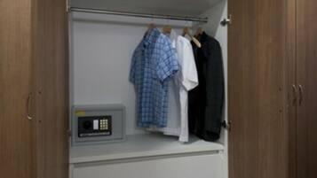 A walk-in closet with wooden doors, a white interior, and a control panel on the lower shelf.