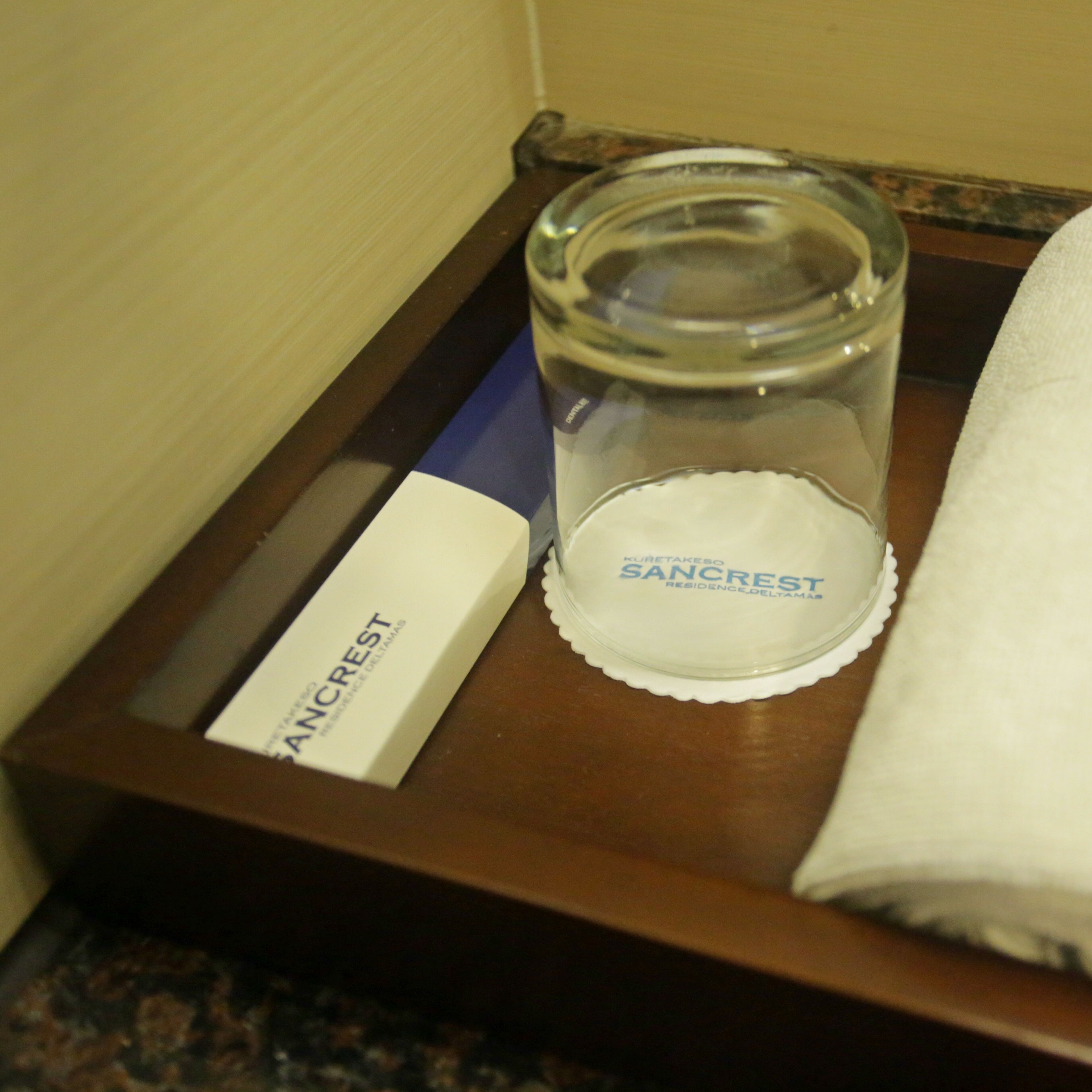 Una bandeja con un candelabro de vidrio, una caja con la etiqueta 'SANCREST' y una toalla blanca.