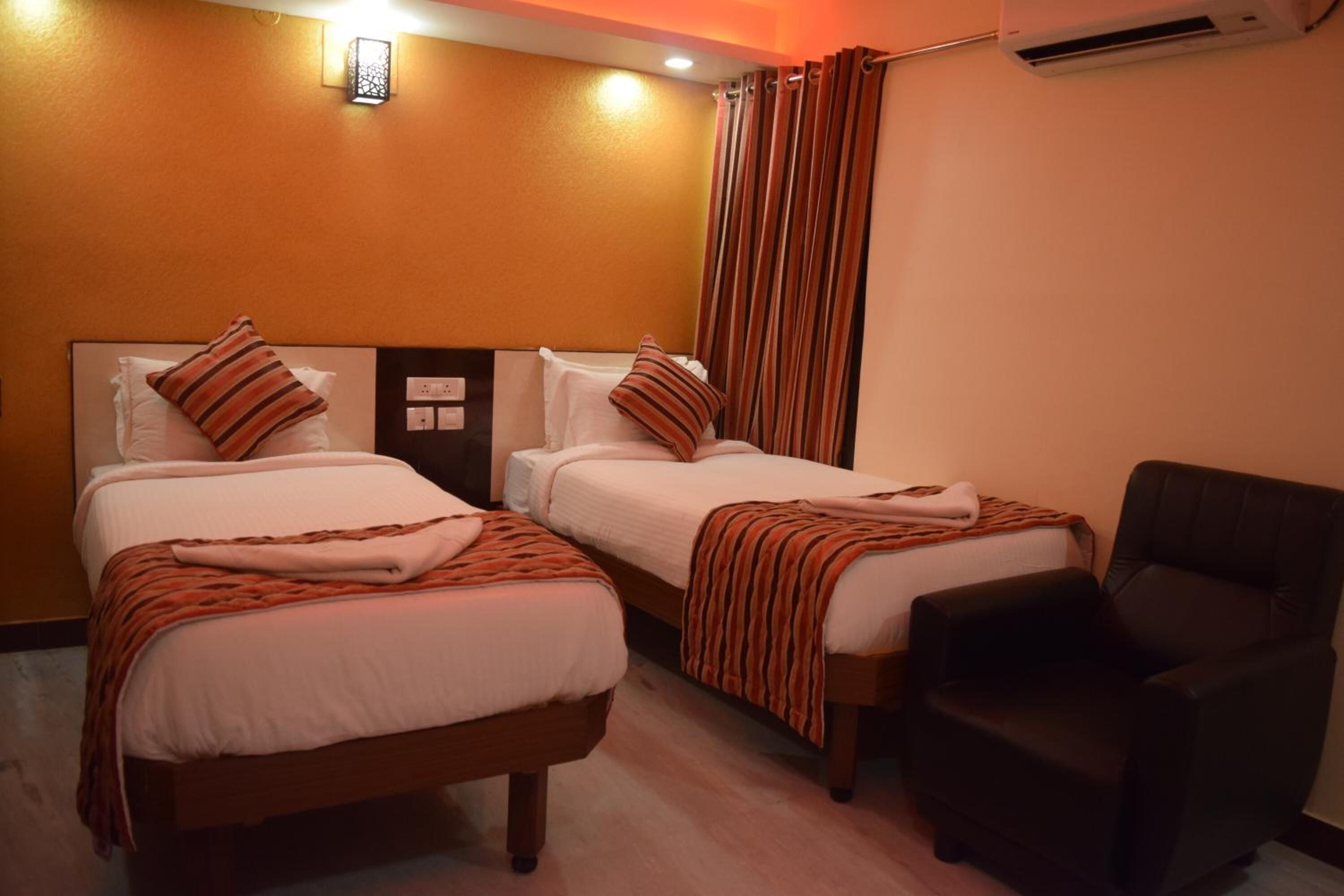 Une chambre d’hôtel avec deux lits, une chaise et un appareil de climatisation.