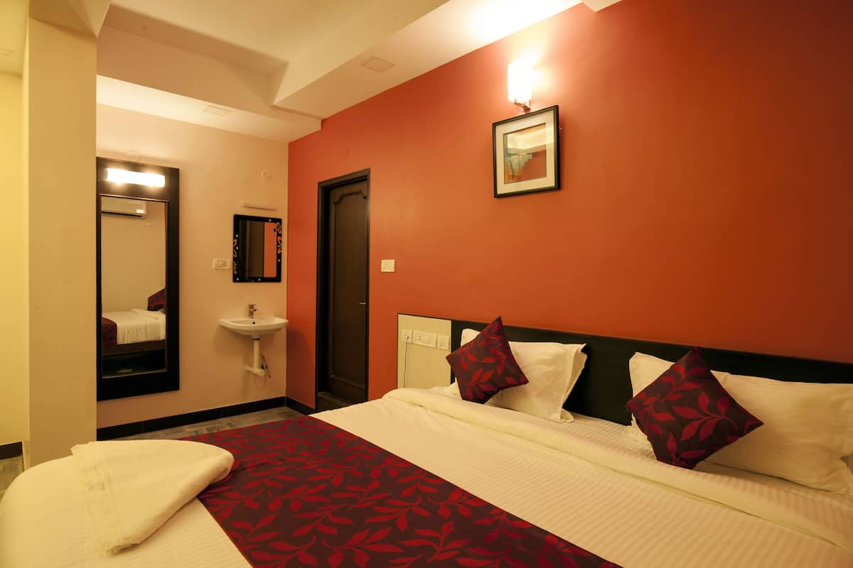 A hotel room with a bed, a bathroom with a sink, and a mirror.