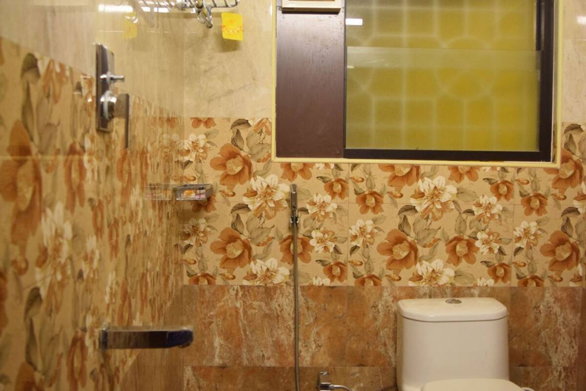 A bathroom with a toilet, bidet, shower, and a window.