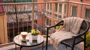 A balcony with a round table, a chair, a potted plant, and a cup of coffee. - Bayers Boardinghouse & Hotel (Munich)