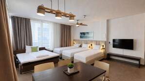 A hotel room with two beds, a dining table, a TV, and a ceiling fan. - Bayers Boardinghouse & Hotel (Munich)