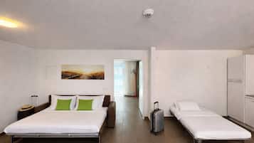 A hotel room with a large bed, a smaller bed, a suitcase, a wardrobe, and a painting on the wall.
