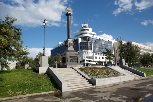 Stunning building with a central column and curved facade, set amidst a beautifully manicured lawn and vibrant flowers.