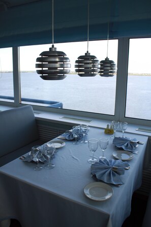 A table set for dining with a view of the water outside.