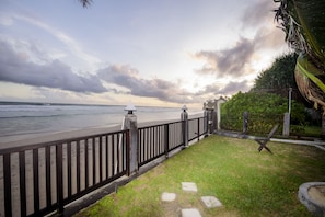 A coastal walkway with a wooden railing, a grassy area, and a view of the ocean.