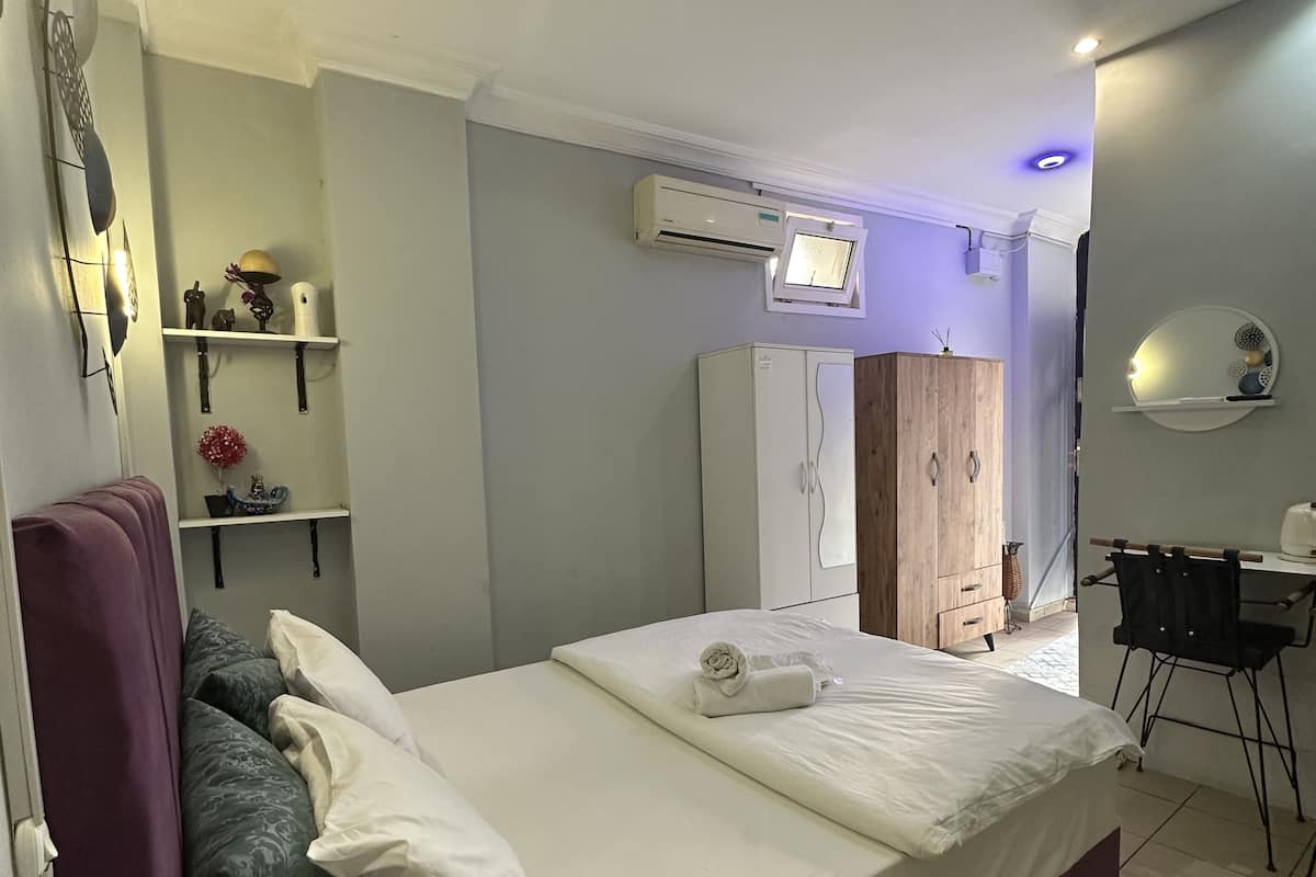 A neatly arranged bedroom with a bed, a desk, and a wardrobe.