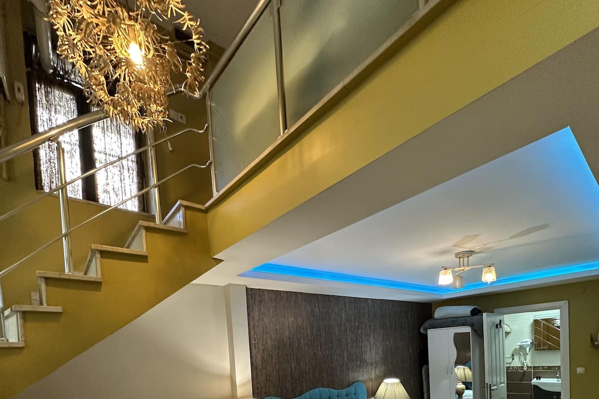 A modern bedroom with two beds, a staircase, and a skylight.