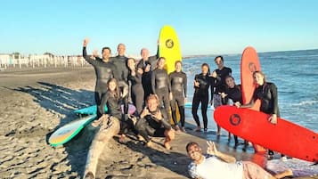 A group of people on a beach with surfboards, some lying on the sand and others standing.